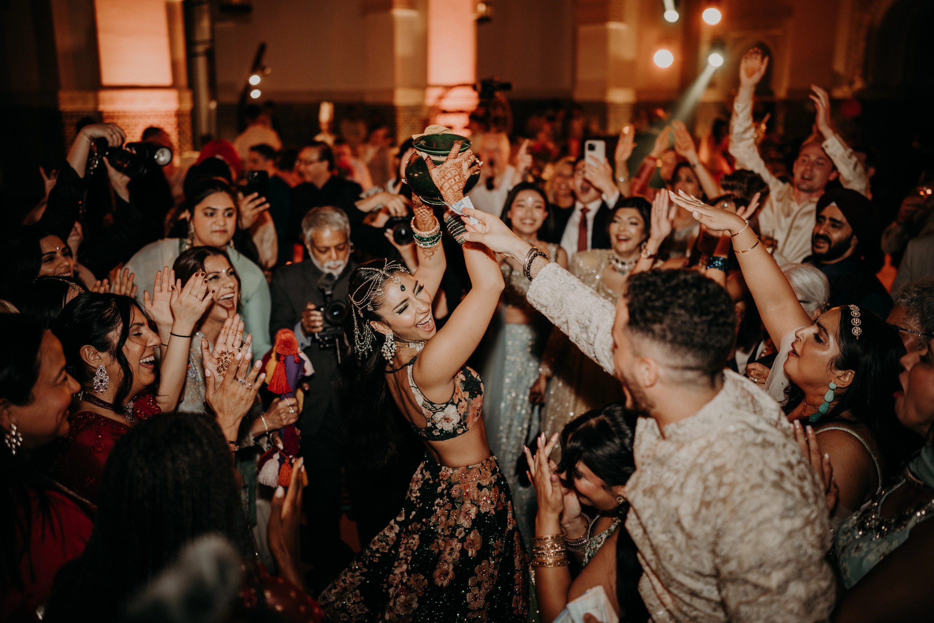 Picture of a newly married couple dancing while surrounded by happy friends and family members at night.