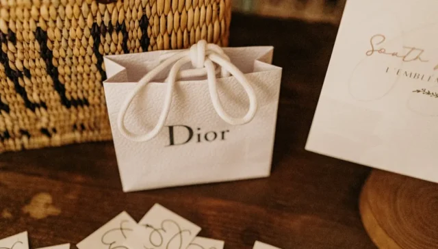 White textured Dior bag on top of a wood table.