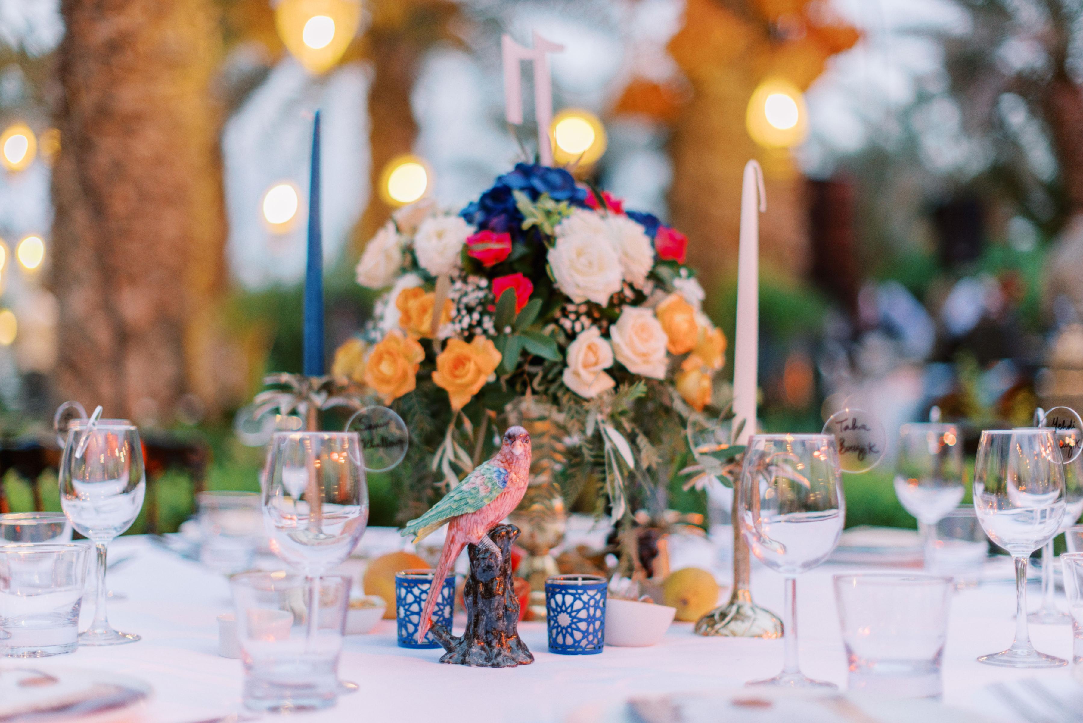 A vase and a bird on a table at a wedding.